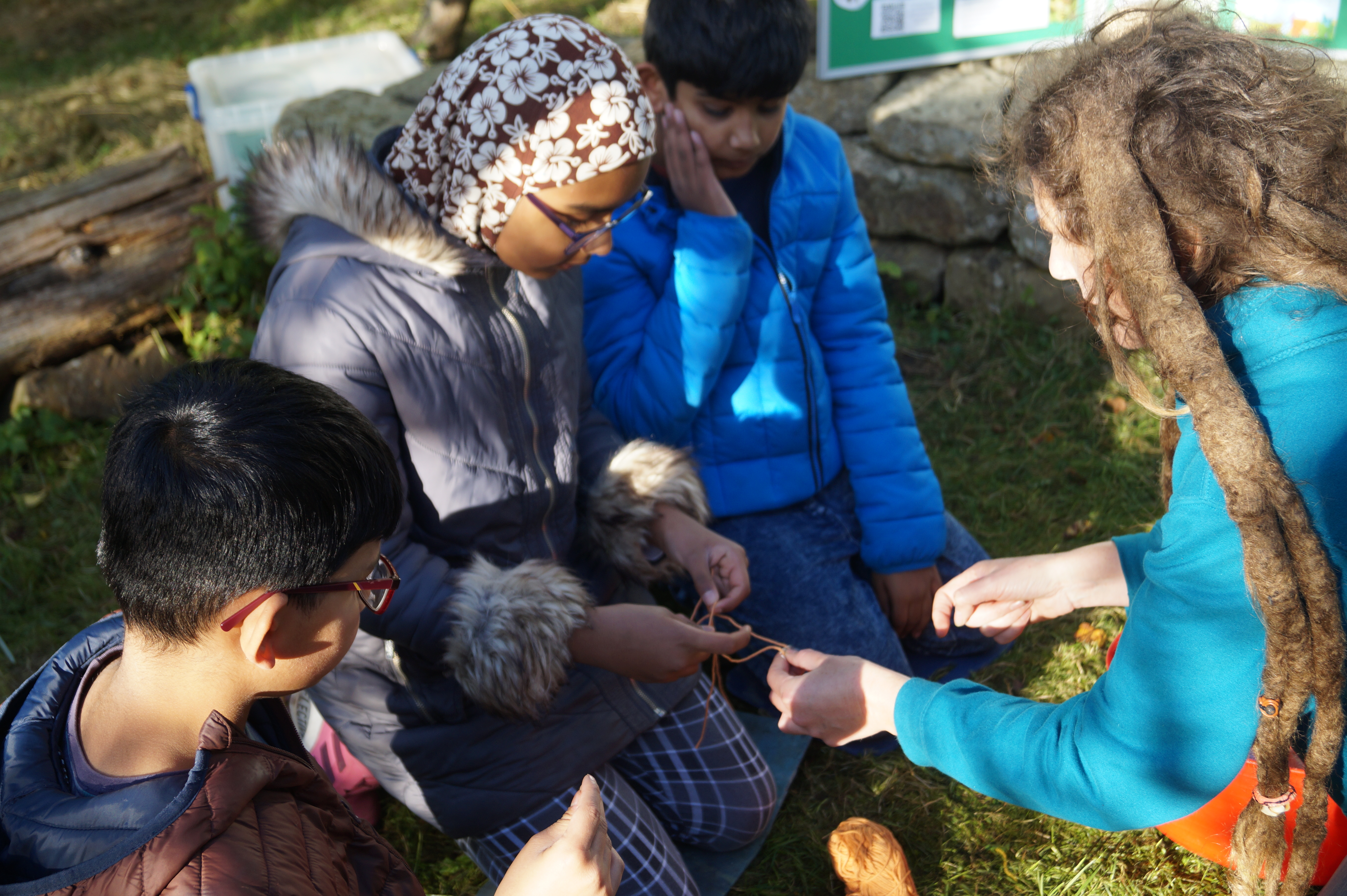 group of children being helped to make craft bees out of wool 