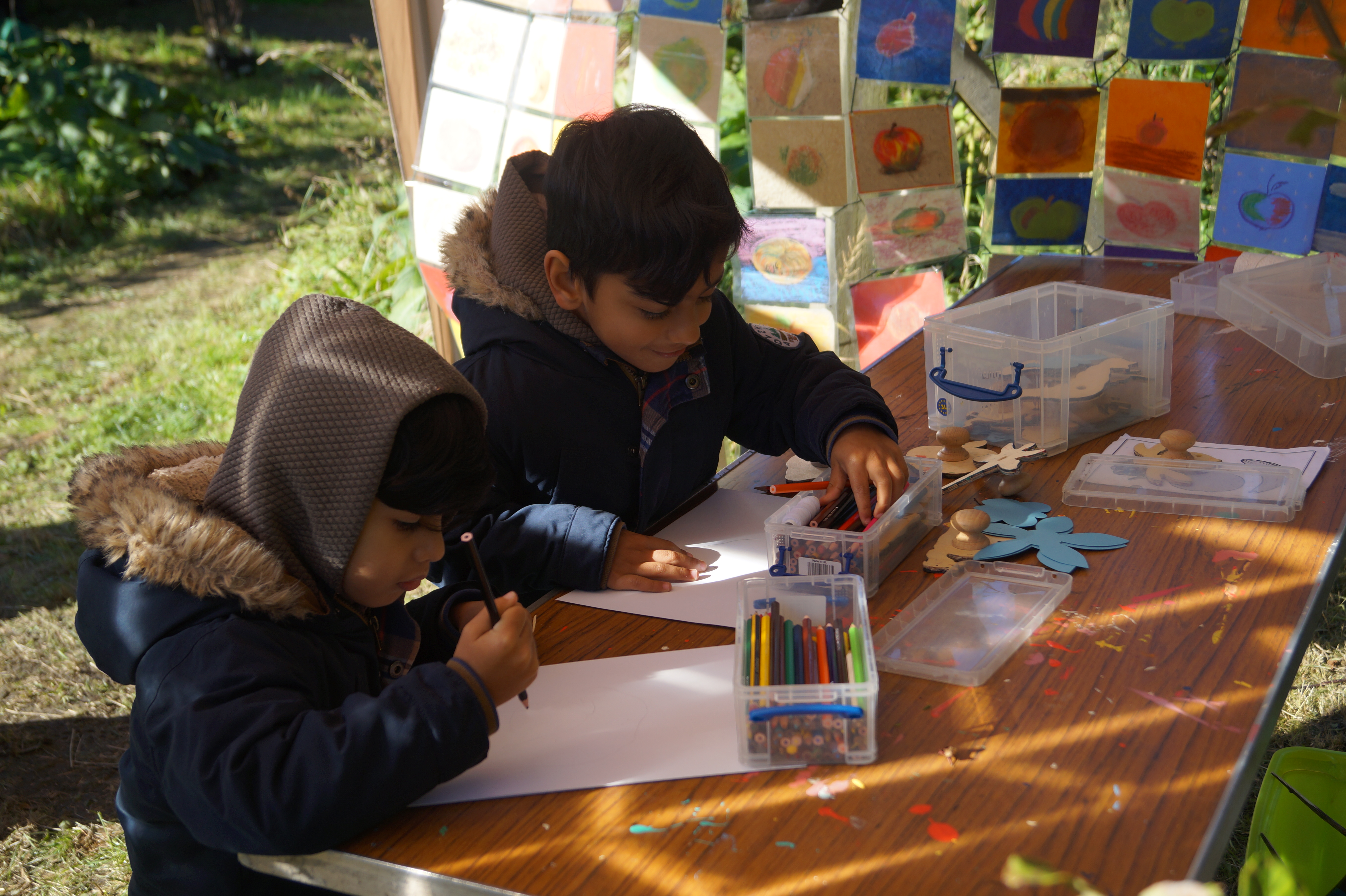 two children choosing pencils to draw at the craft stall
