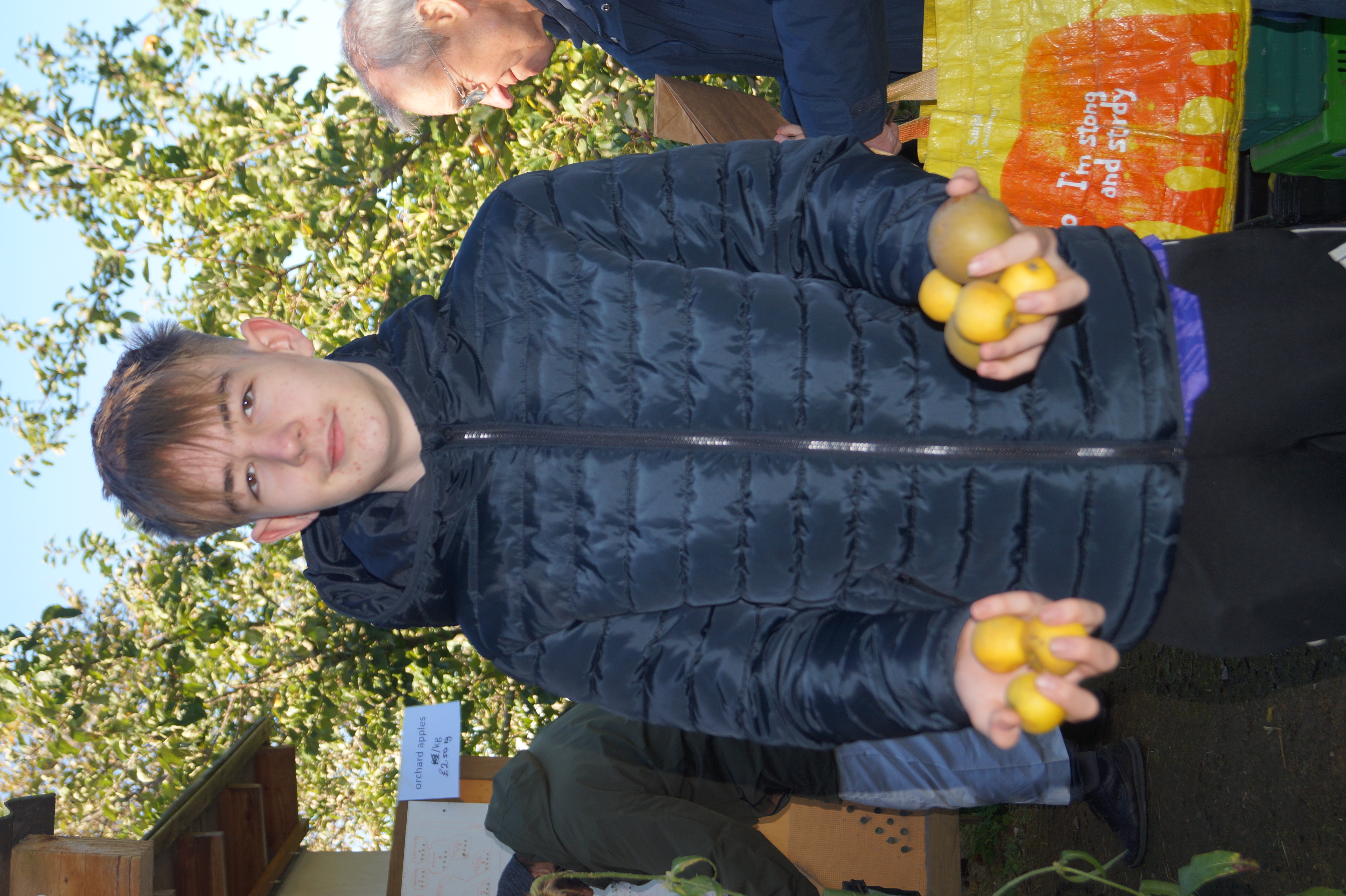 young man holding apples in his hands, people behind queing to buy apples