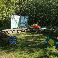 Stone bench surrounded by trees with info board and signs for Bee Club