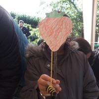 child holding a cardboard strawberry they have made infront of them like a mask